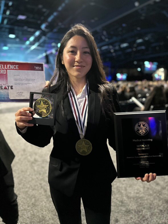 Anna Seavey holds her International Leadership Convention (ILC) medical assisting division awards after she won first place in Houston, Texas. Seavey worked hard to secure her win, prior to the competition she was a part of a medical assisting program and did 100 hours of a volunteering internship for her HOSA class. Her win was widely celebrated by not only Kalani students, but all of the students from Hawaii and in the Stadium. 