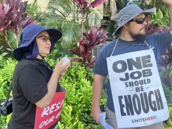 Gerritt Vincent (right) and Leizel Manayan (left), two workers for the Hilton Hotels, stand outside of the Hilton Hawaii Village Waikiki Beach Resort chanting protests. Both wear homemade signs of their arguments. Over 2,000 Hilton employees have been on strike since Monday, Oct. 23, fighting for two main things, better wages and more hours. 