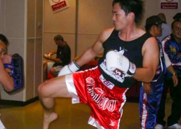 Arthur Wong kicks the pads in his Muay Thai shorts and gloves.